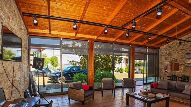 A spacious lobby with a wooden ceiling, large windows, and a seating area with a sofa and chairs. - Hotel Rural Quinta de S Sebastiao (Viana do Castelo)