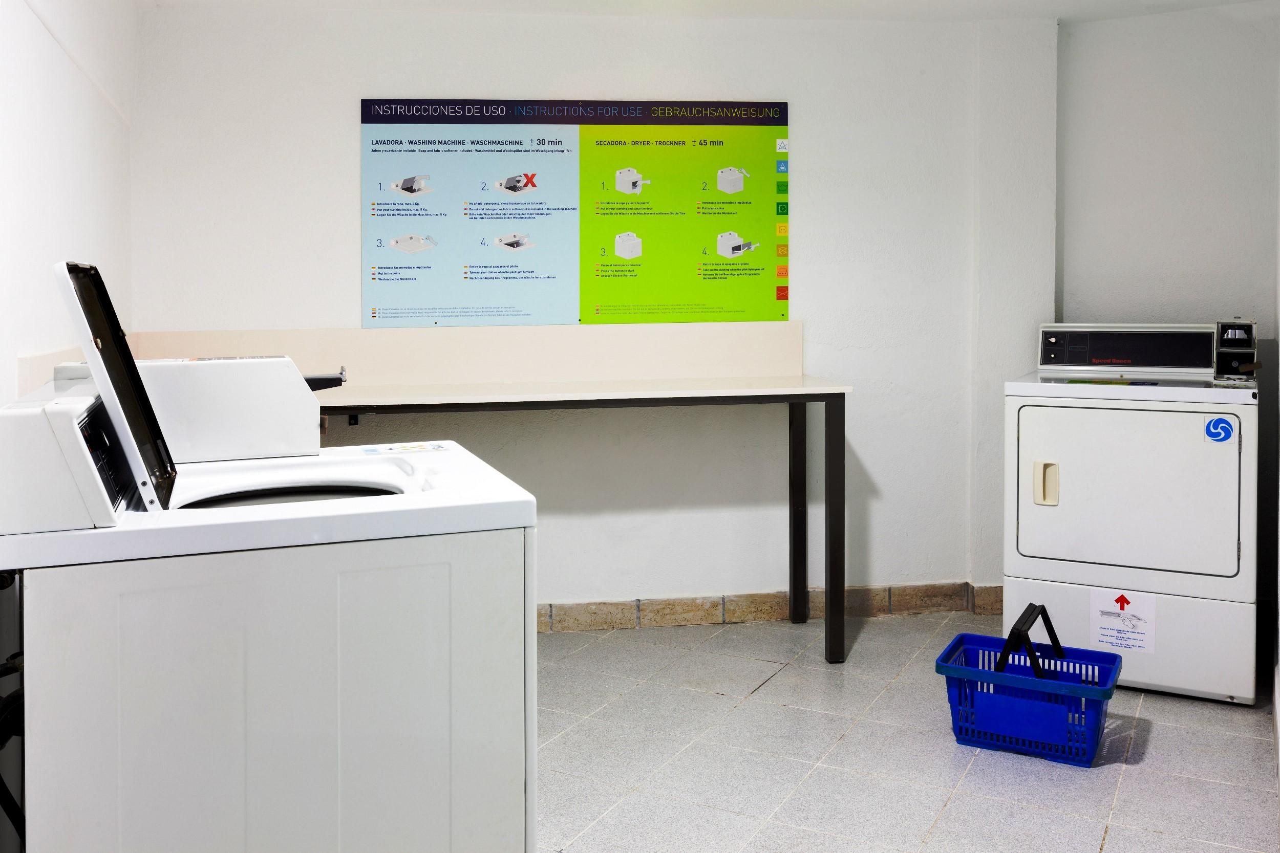 A laundry room with a washing machine, dryer, and a wall-mounted instruction poster.