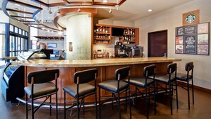 A bar area with a curved counter, bar stools, and shelves stocked with bottles.