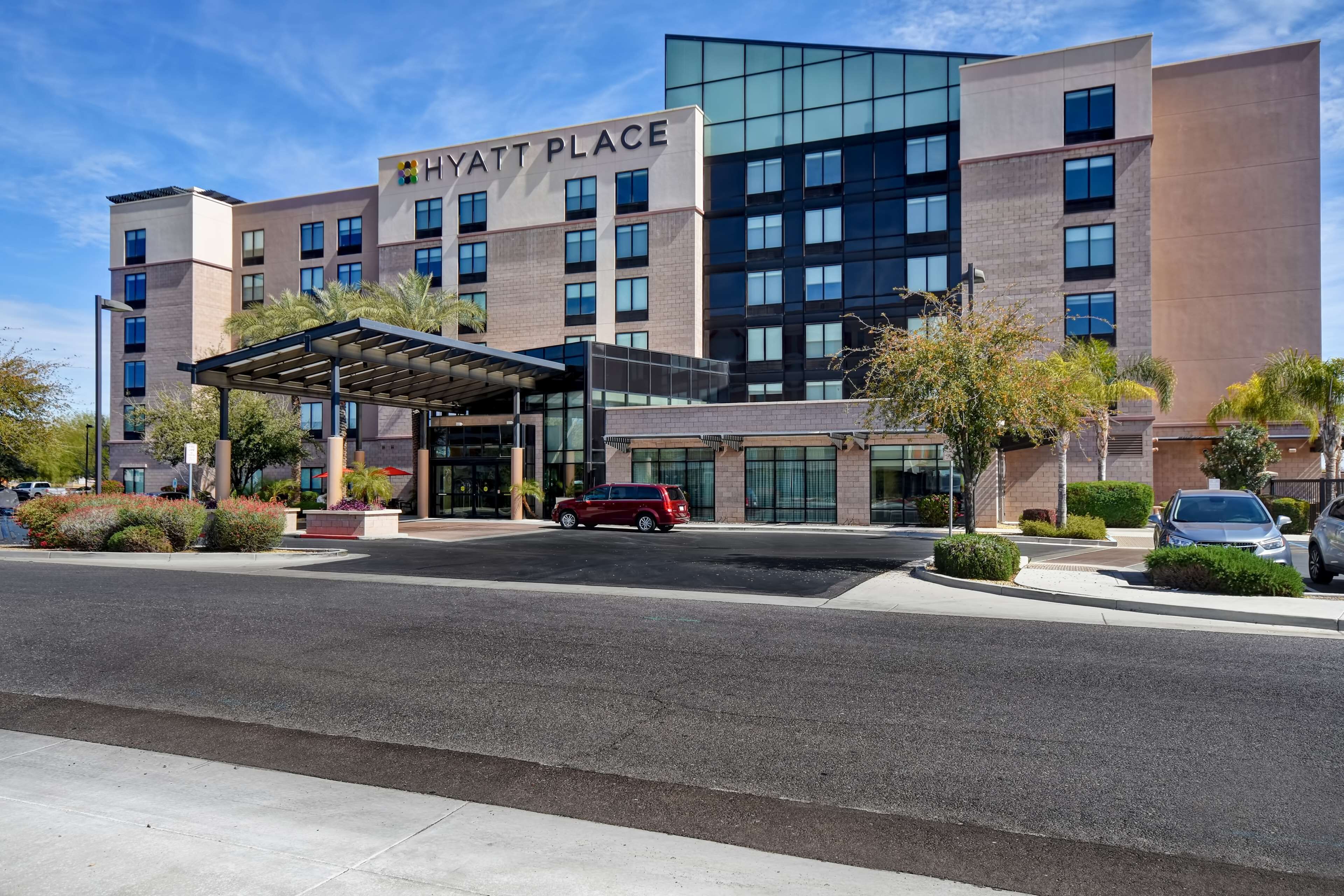 A multi-story hotel with a covered entrance and a parking area.