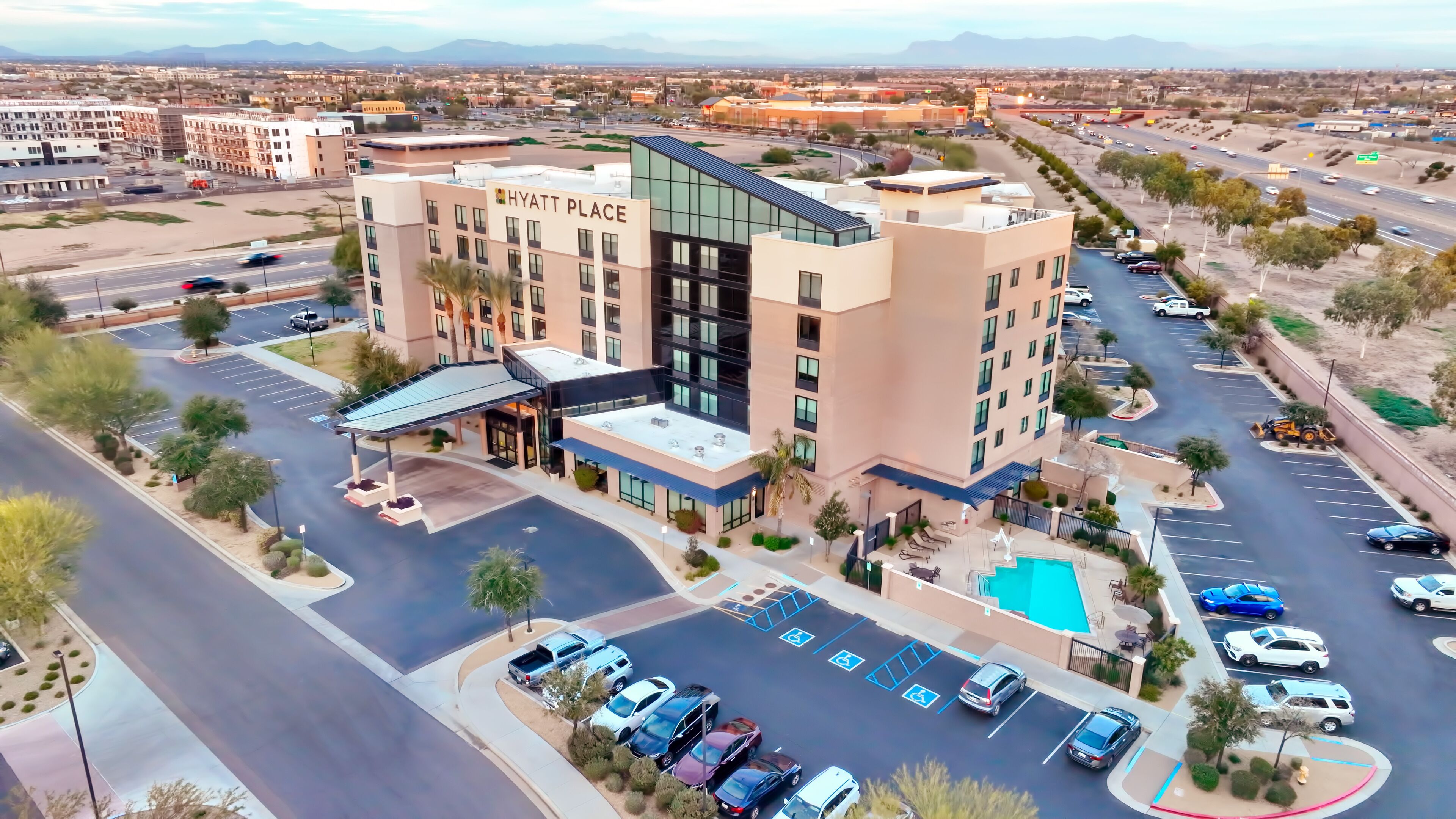 A multi-story hotel with a rooftop pool and a parking lot.