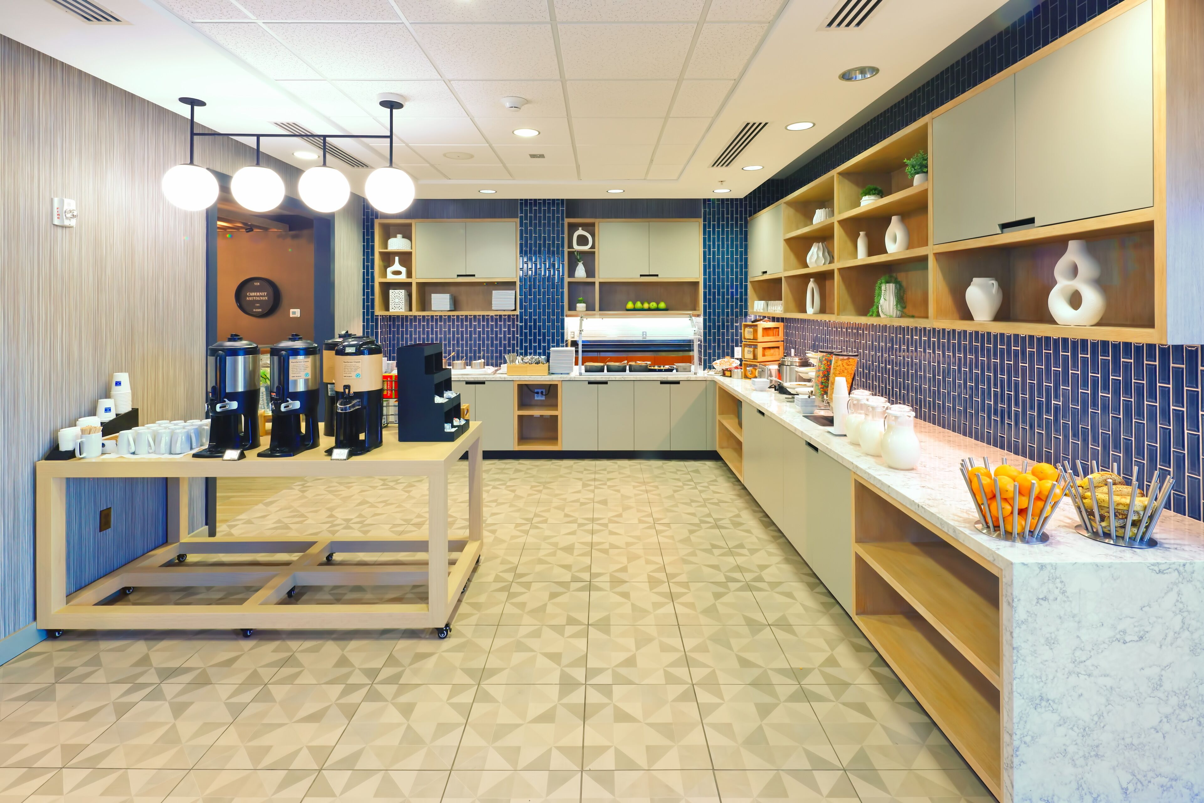 A modern cafe with a counter, coffee machines, and a variety of food items displayed.