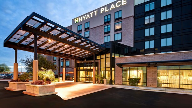 A modern hotel entrance with a covered walkway, large windows, and a well-lit facade.