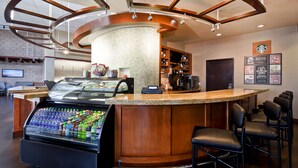 A modern bar area with a curved counter, a beverage dispenser, and bar stools.