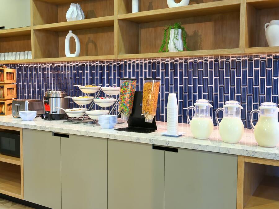 A kitchen counter with various food items and containers, a coffee machine, and a tiled backsplash.