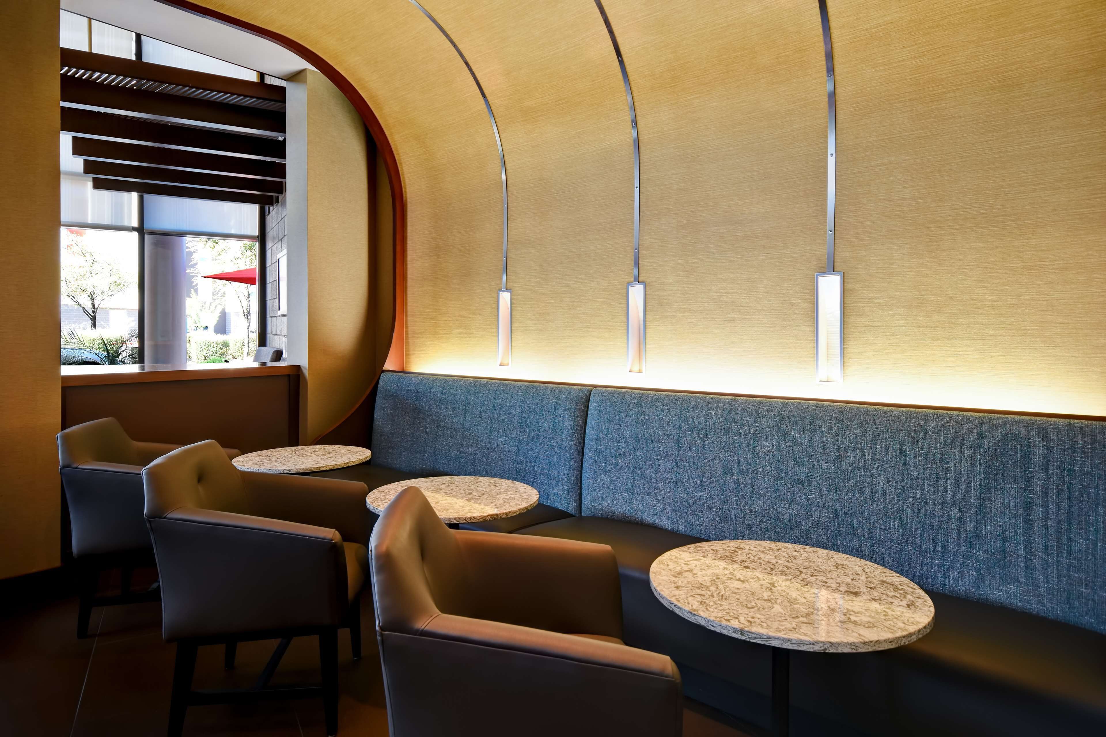 A modern interior with a curved wall, a seating area with a sofa and armchairs, and two round tables.