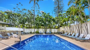 A swimming pool with lounge chairs and palm trees. - The Gardens at West Maui (Lahaina)