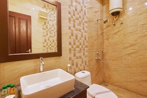 Een badkamer met een marmeren wand, een wastafel, een toilet en een spiegel.