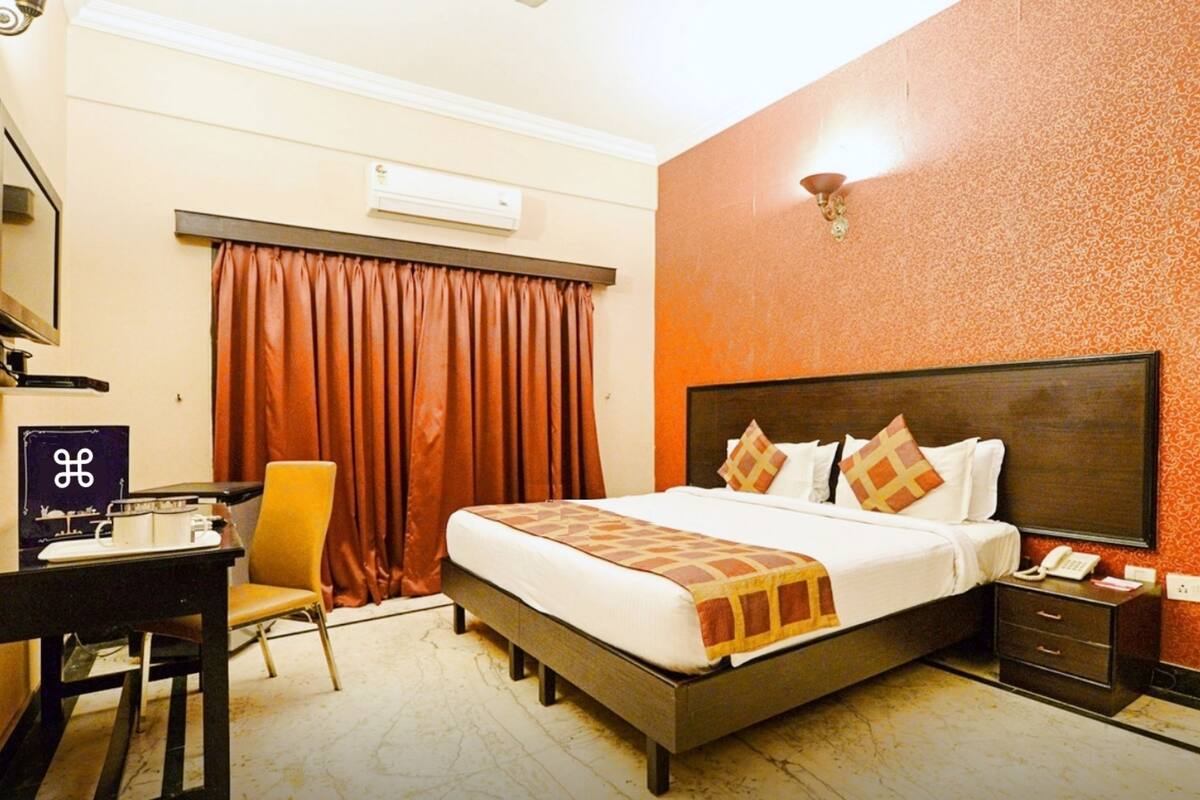 Een hotelkamer met een bed, een bureau, een stoel, een televisie, een telefoon en een deur.