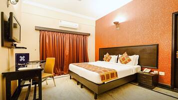 Habitación de hotel con cama, escritorio, silla, televisor, teléfono y puerta.