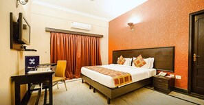 Een hotelkamer met een bed, een bureau, een stoel, een televisie, een telefoon en een deur.