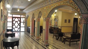 A spacious lobby with a marble floor, ornate columns, and traditional furniture. - Hotel Sajjan Niwas (Jaipur)