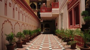 A corridor with a checkered floor, potted plants, and traditional architectural elements. - Hotel Sajjan Niwas (Jaipur)