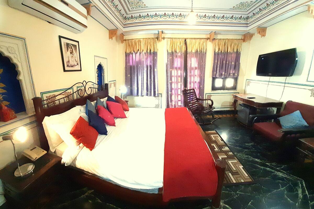 Une chambre d’hôtel avec un grand lit, un bureau, une télévision et un coin salon.