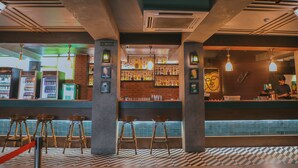 Zona de bar con taburetes, una barra y diversas botellas.