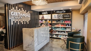 Interior de salón con mostrador de recepción, exhibición de productos L'Oréal Paris y Kérastase, y zona de estar.