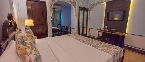 A hotel room with a large bed, a TV, a desk, and a mirror.