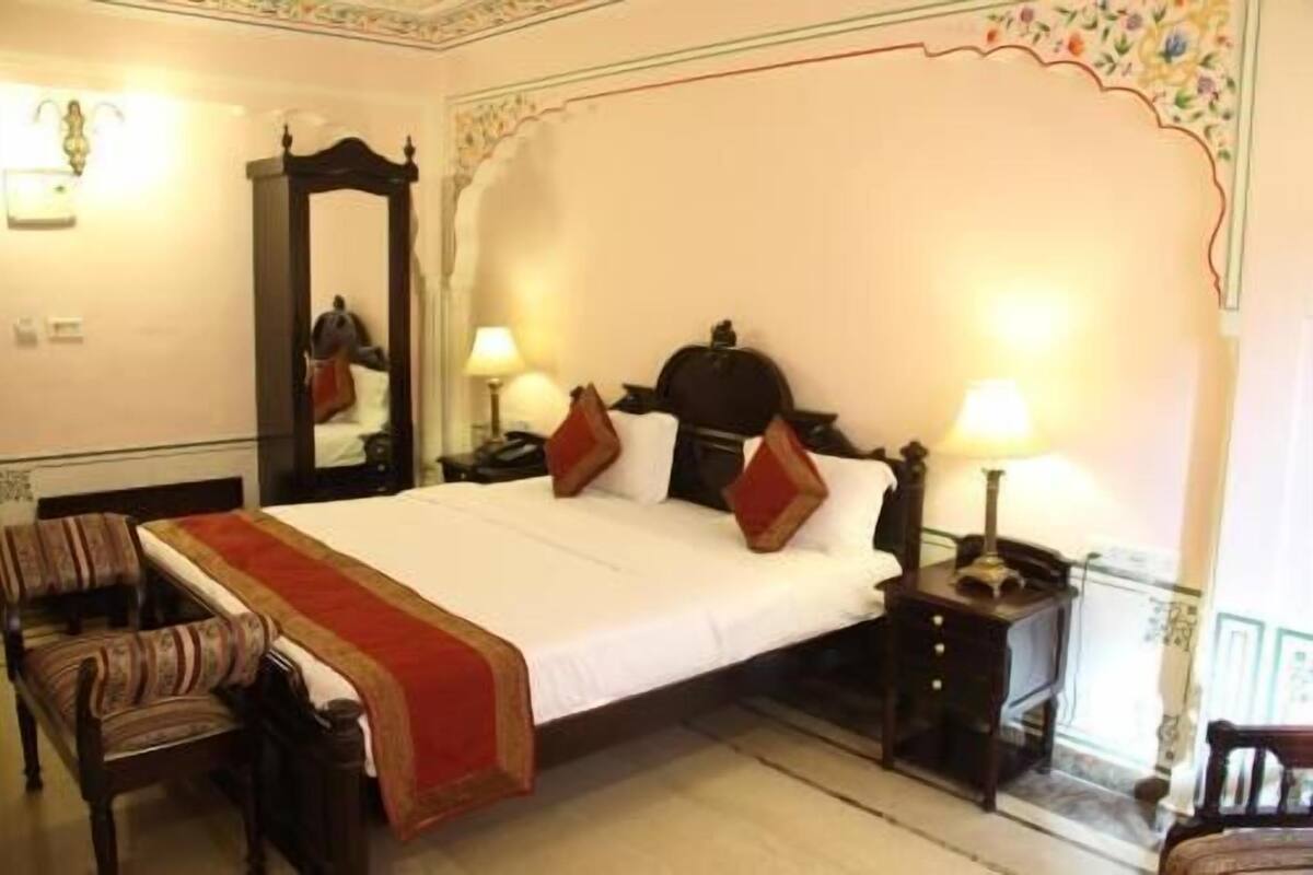 A hotel room with a large bed, two bedside tables, a chair, and a mirror.