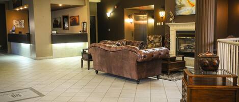 A lobby with a leather sofa, a fireplace, and a reception desk.