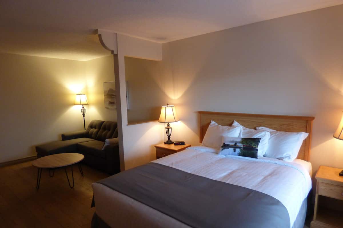 Une chambre d’hôtel avec un grand lit, deux lampes de chevet, une petite table ronde, un canapé et une chaise.
