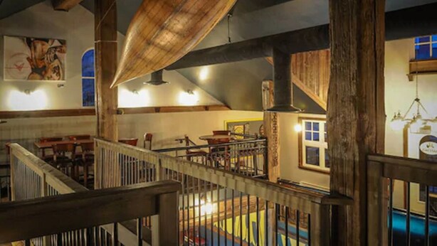 Habitación con vigas de madera a la vista, una escalera y zona de piscina.