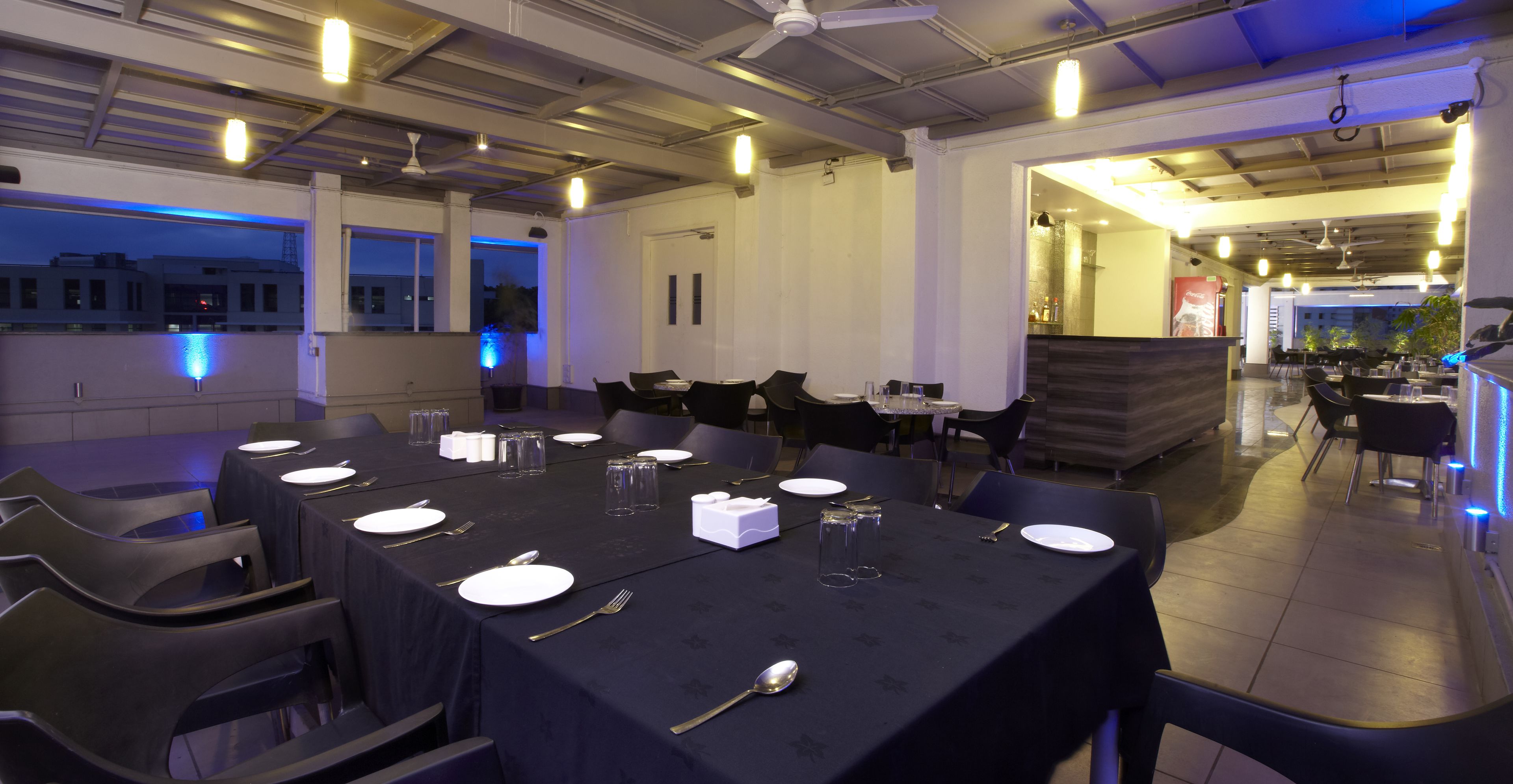 Un restaurant avec des tables dressées, des chaises et un ventilateur de plafond.