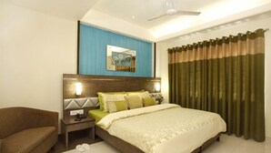 Una habitación de hotel con cama, mesita de noche, silla, espejo y ventana con cortinas.