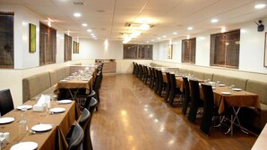 Un salón de conferencias con mesas largas, sillas y suelo de madera.