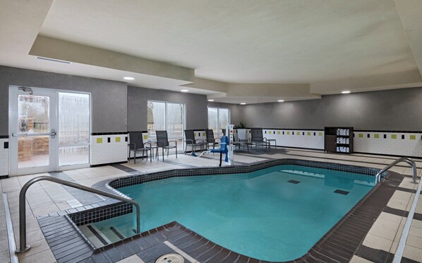 Une piscine dotée d’une terrasse carrelée, de chaises et d’un vestiaire.
