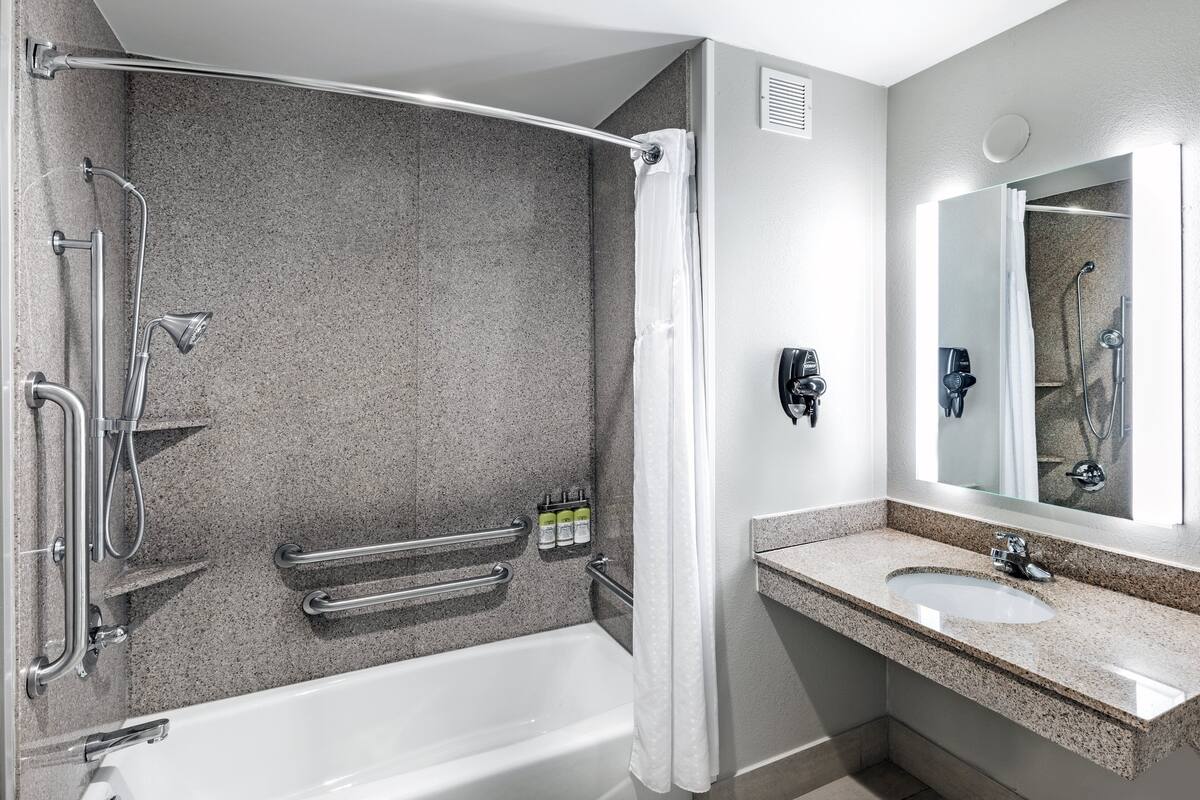 A modern bathroom with a bathtub, shower, and vanity.