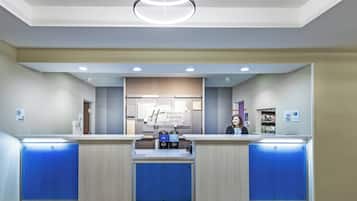 Un espace d’accueil d’hôtel avec un comptoir, une enseigne indiquant « Holiday Inn Express & Suites », et une caméra de surveillance fixée au mur.