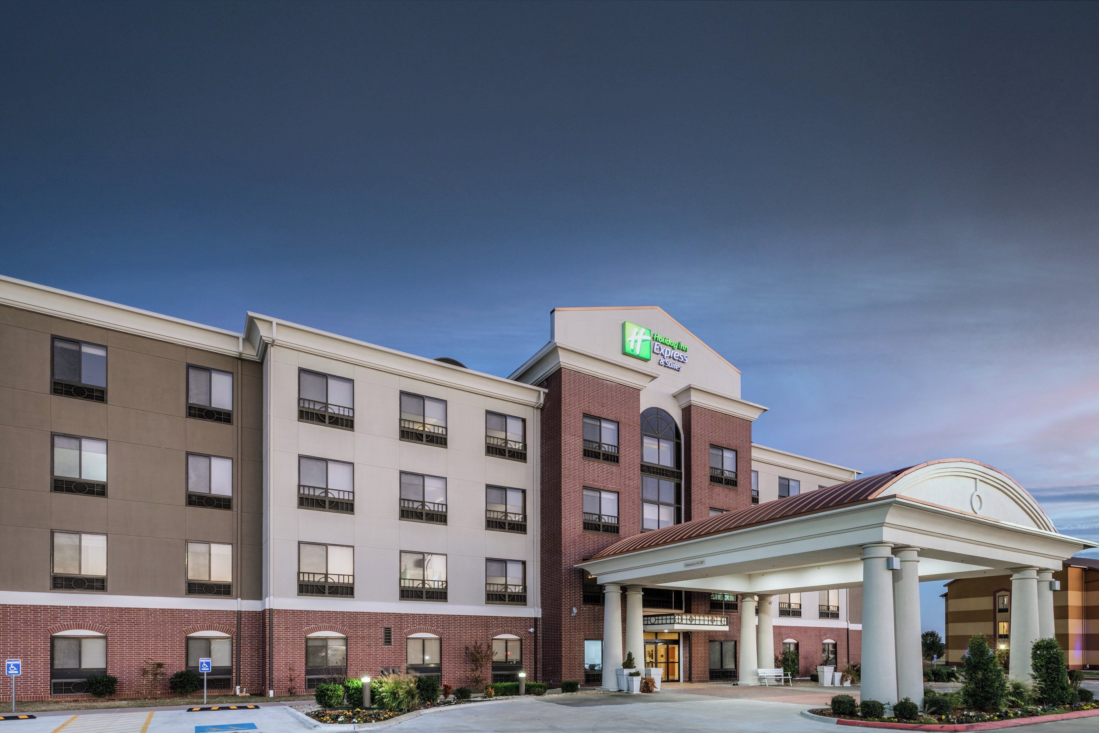 A Holiday Inn Express & Suites hotel with a brick facade, multiple windows, and a covered entrance.
