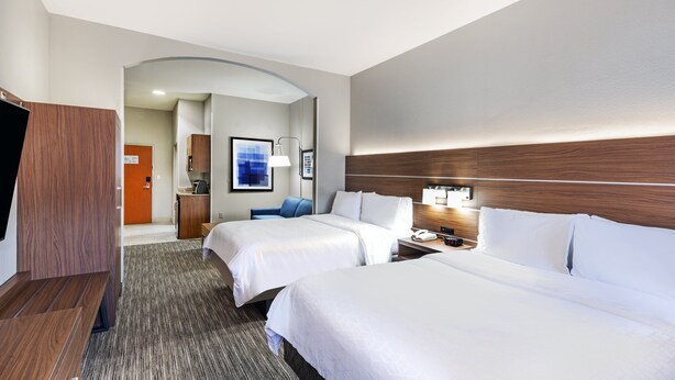 Ein Hotelzimmer mit zwei Betten, einem Schreibtisch, einem Stuhl und einem Fernseher.
