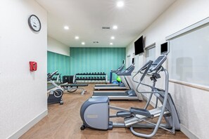 Un gimnasio con cintas de correr, elípticas y pesas sueltas.