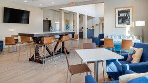 A modern hotel lobby with a bar area, seating arrangements, and a television. - The Inn at Leonardtown, an Ascend Collection Hotel (Leonardtown)