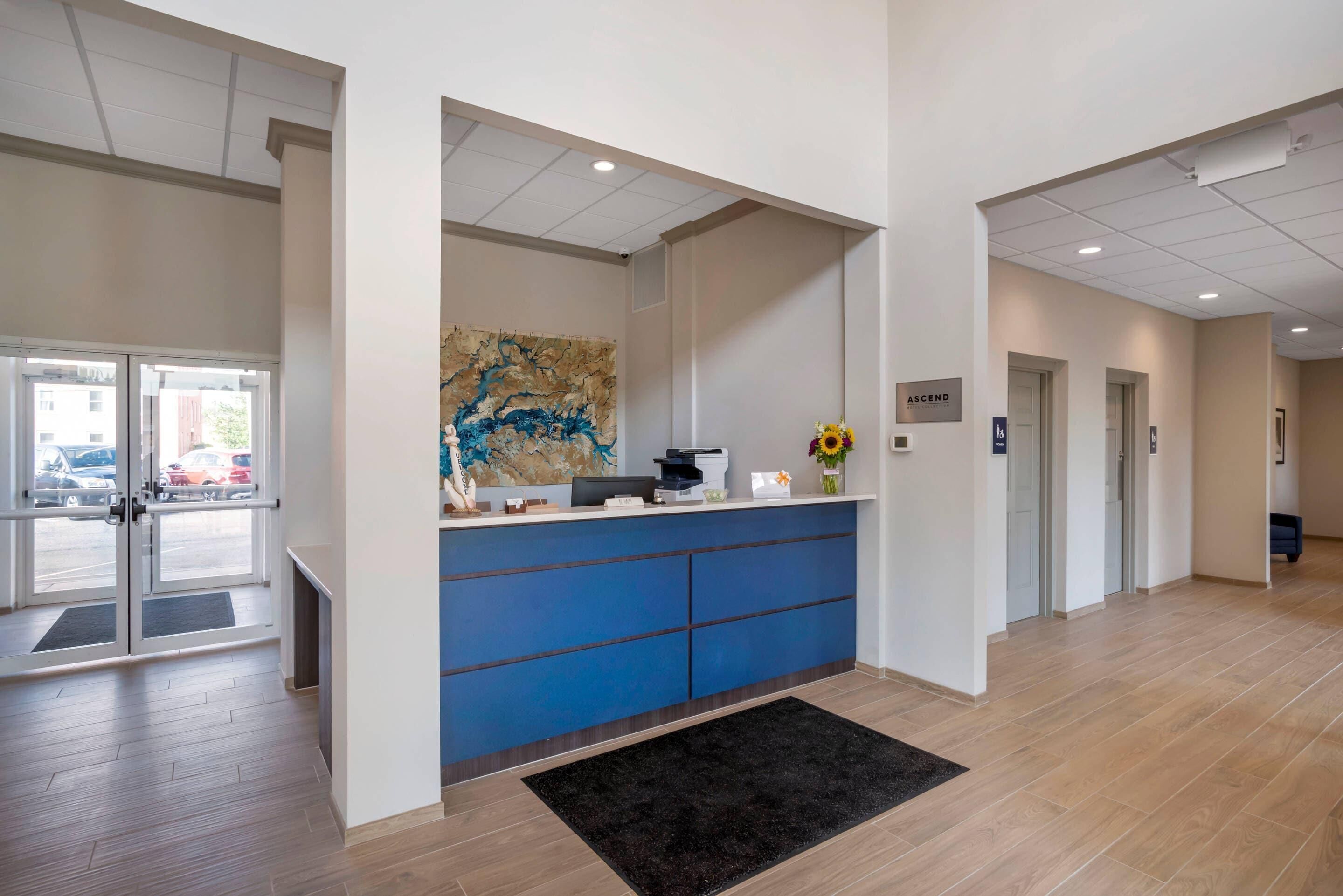A reception area with a blue counter, a large abstract painting, and a sign that says "ASCEND".