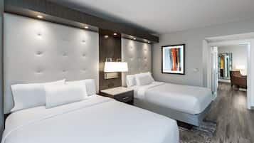 Habitación de hotel con dos camas, una mesita de noche, una lámpara y un cuadro abstracto en la pared.