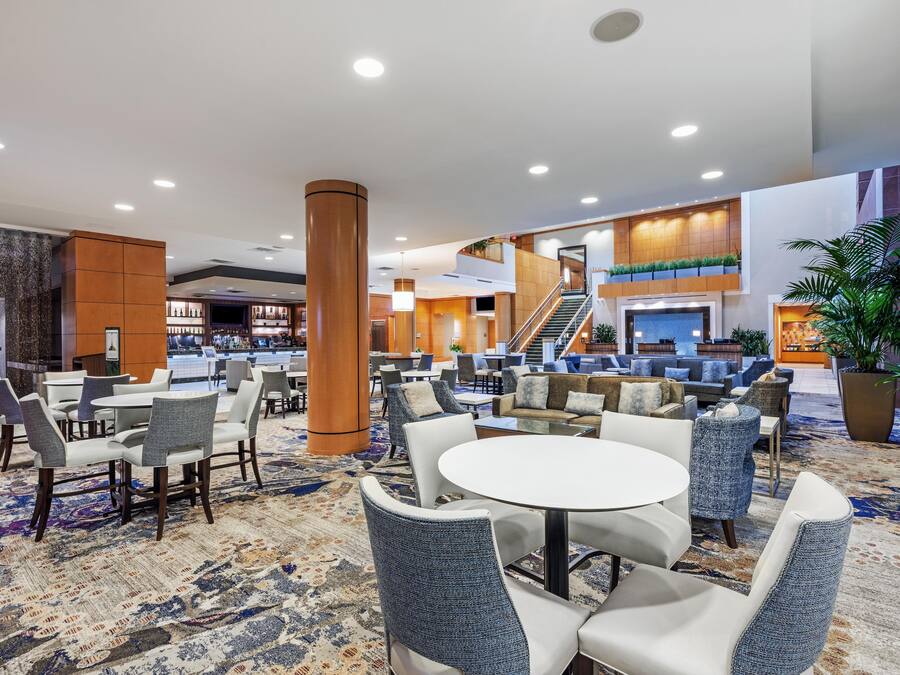 Een hotel lobby met een bar, zitgedeeltes en een trap naar een hoger gelegen verdieping.