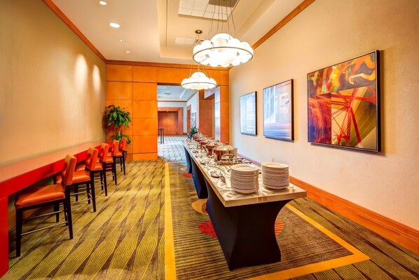 A hotel corridor with a long reception desk, chairs, and a buffet setup.