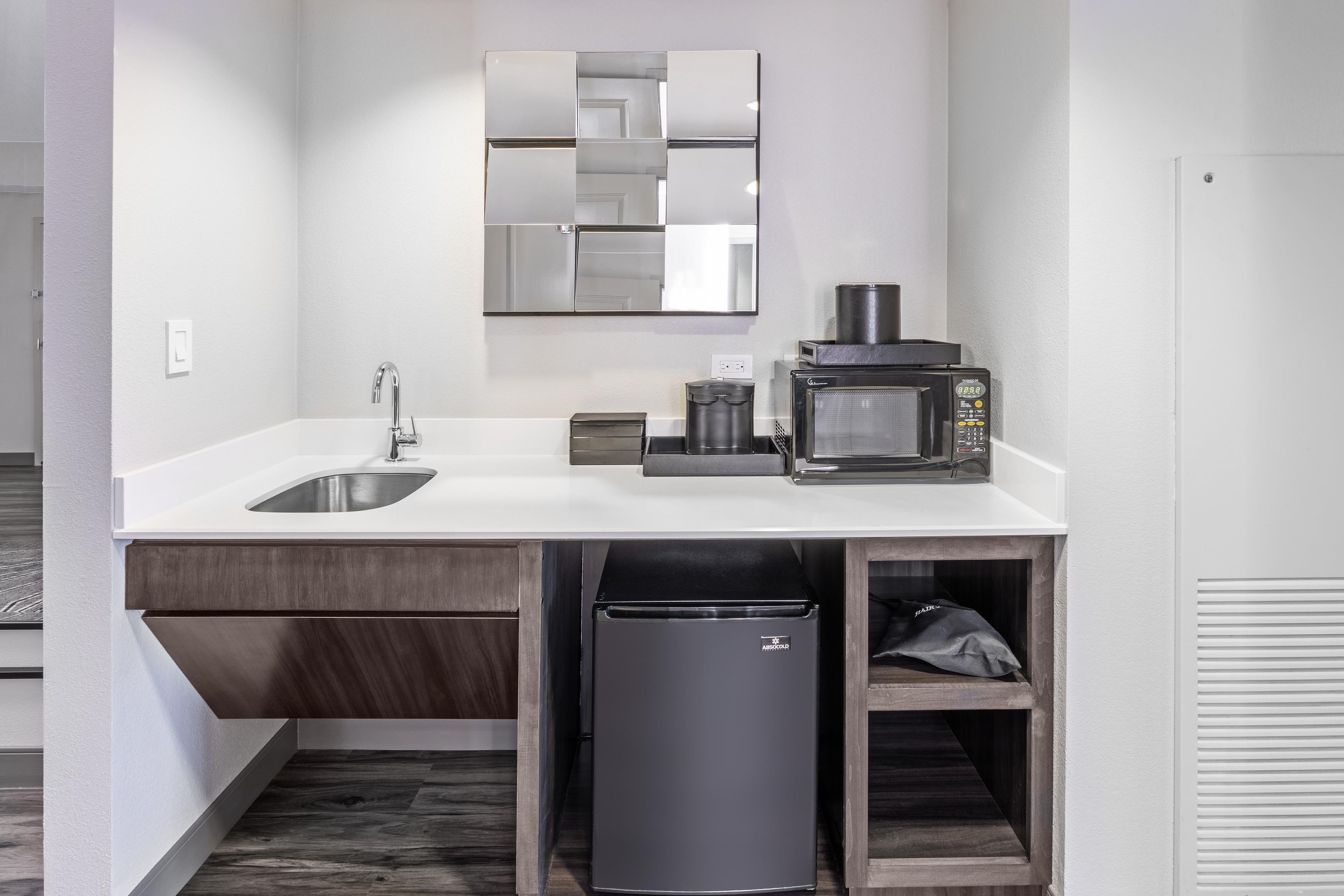 A modern kitchen with a built-in sink, a coffee machine, and a trash bin.