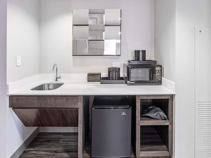 A modern kitchen with a built-in sink, a coffee machine, and a trash bin.