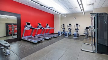 A gym with treadmills, elliptical machines, and a mirrored wall.