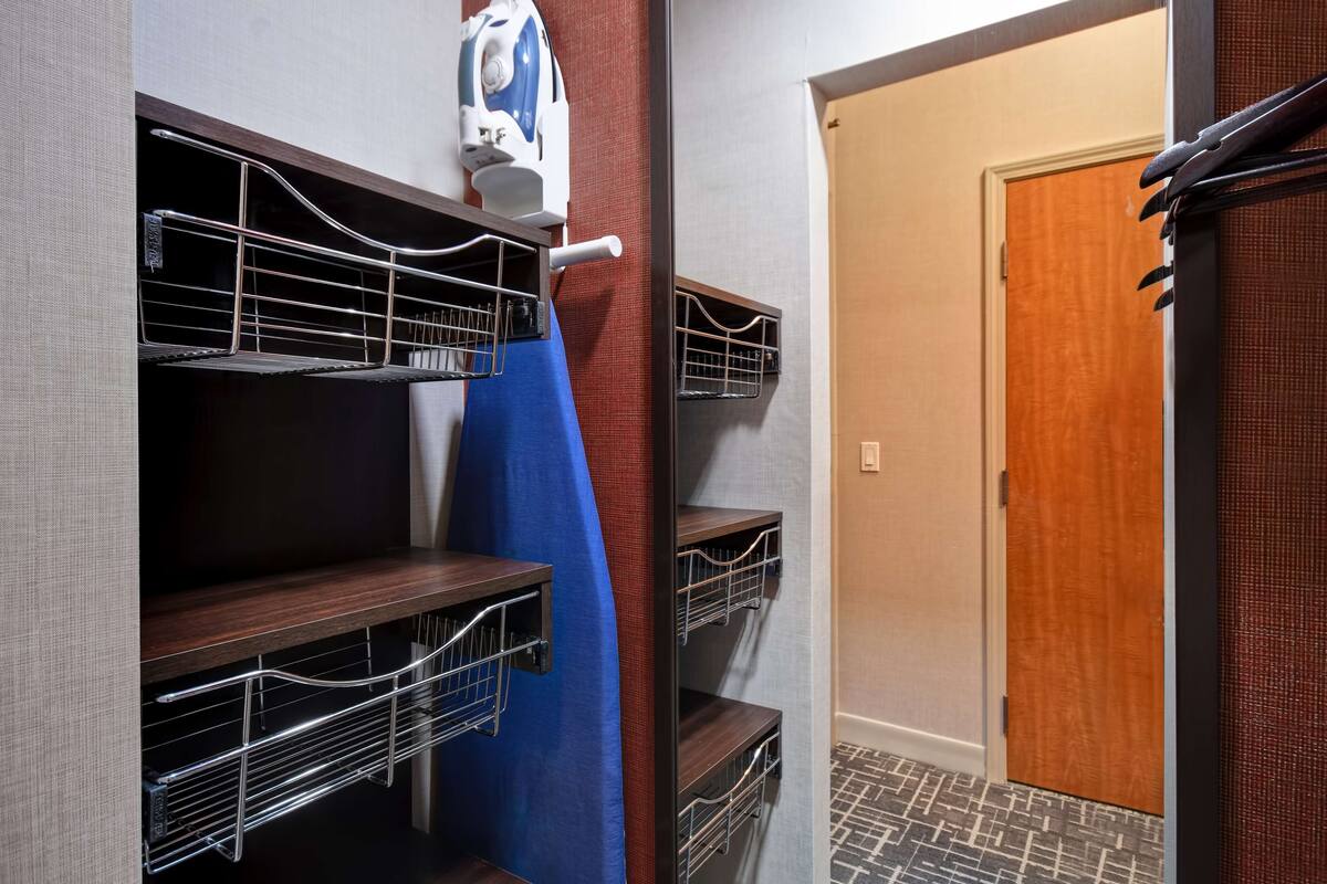 A hotel room with built-in shelves, a blue towel, and a door with a wooden frame.