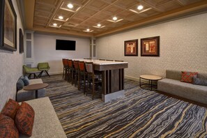Meetings take place around a long, rectangular table in this well-appointed room, surrounded by comfortable seating and artwork on the walls.