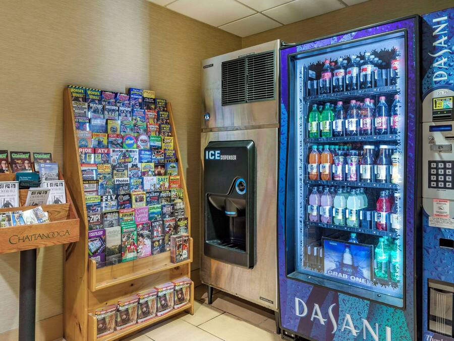 A vending machine with a variety of beverages and a magazine rack filled with travel and entertainment magazines.