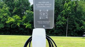 Una stazione di ricarica per veicoli elettrici Tesla, con un cartello che indica il pagamento a consumo.