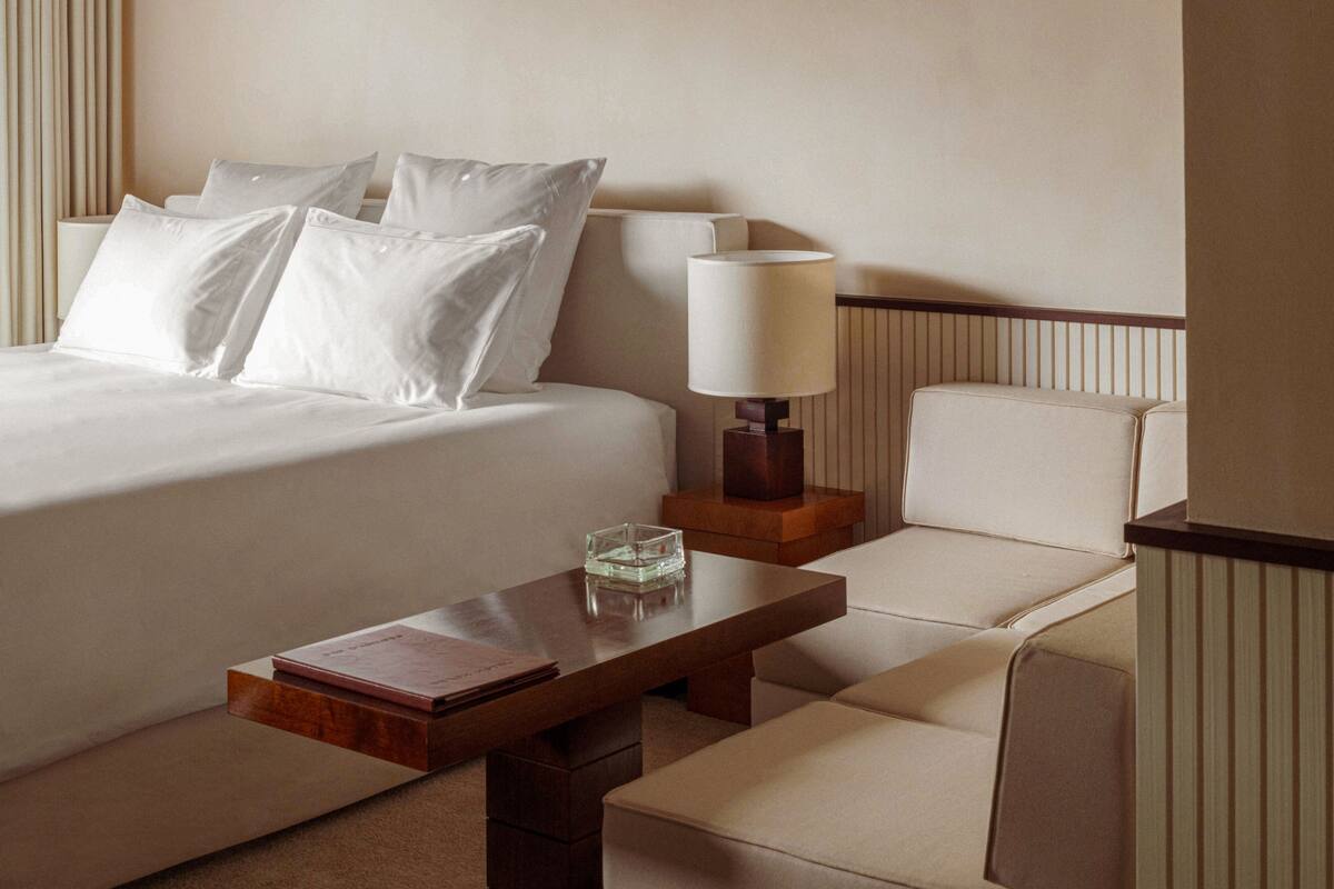 A hotel room with a bed, a nightstand, a lamp, a coffee table, and a sofa.