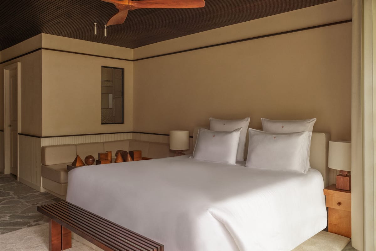 A large bed with white linens, a wooden headboard, and two bedside lamps.
