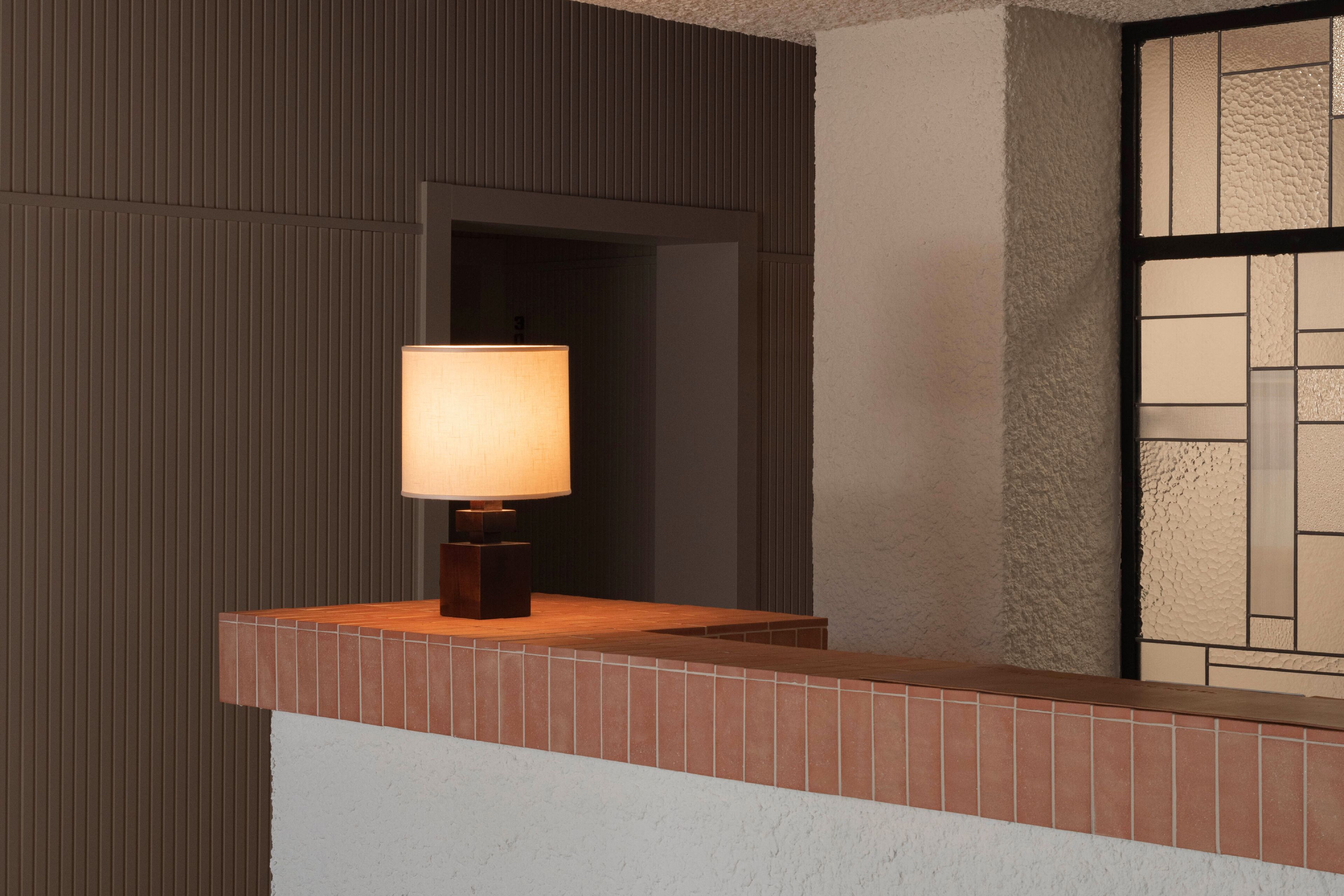 Une salle de bain moderne avec un mur carrelé, un comptoir en bois et une lampe.