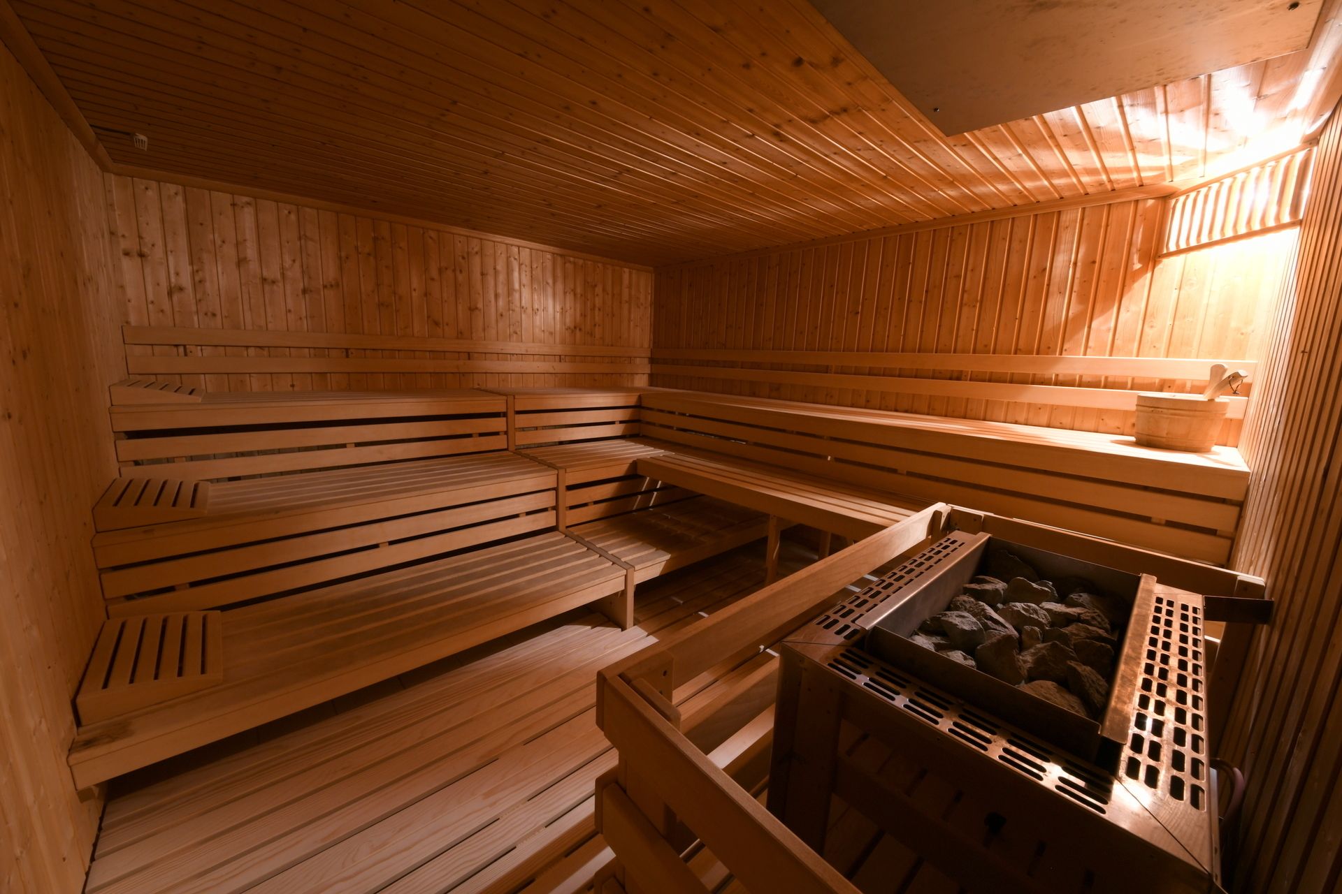 A sauna with wooden benches and a stone basin.